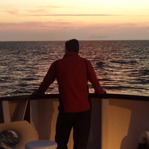 Person watcing the sunset on the main deck of a ship.